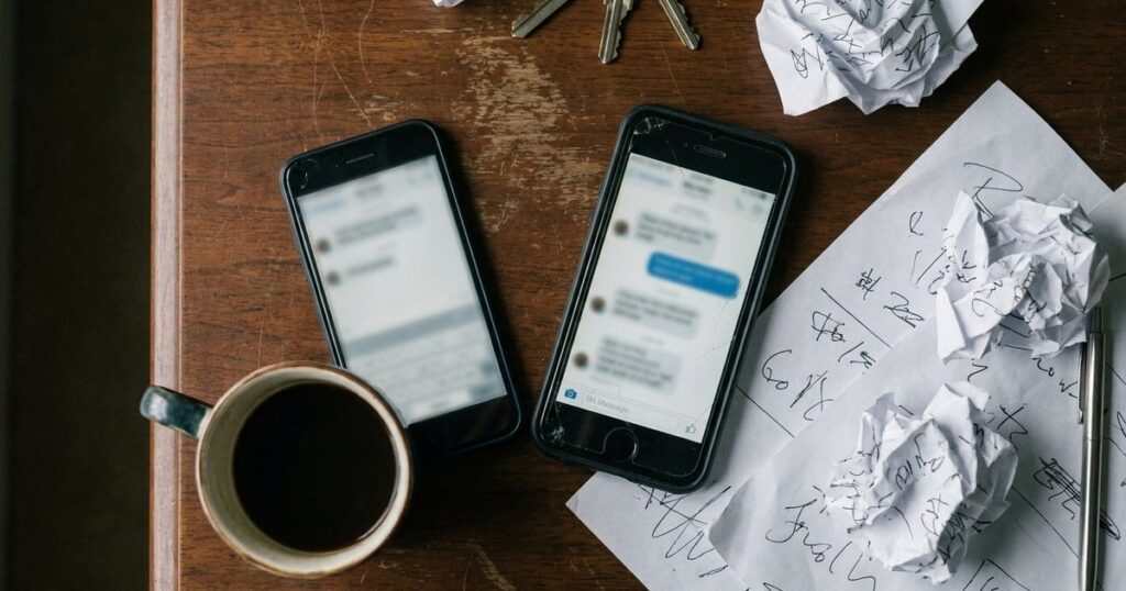 Overhead view of a table with a phone showing a blurred chat, relating to WhatsApp sales follow-up discussions.