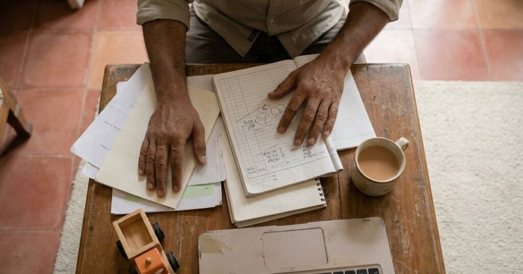 An Indian entrepreneur juggles family and business finances with visible household and work items around, capturing the essence of balancing EMI and family capi