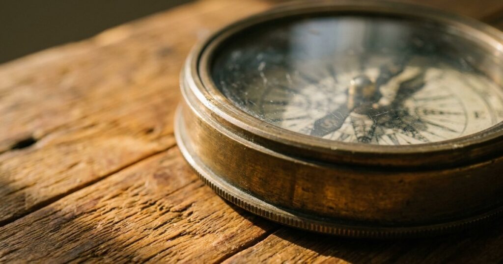 Close-up of a vintage compass on wood, evoking discovery and the article's focus on using questions in sales.