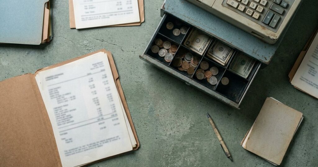 Overhead view of a startup's desk with folders, cash register, and blurred financial statement about using them as management tools.